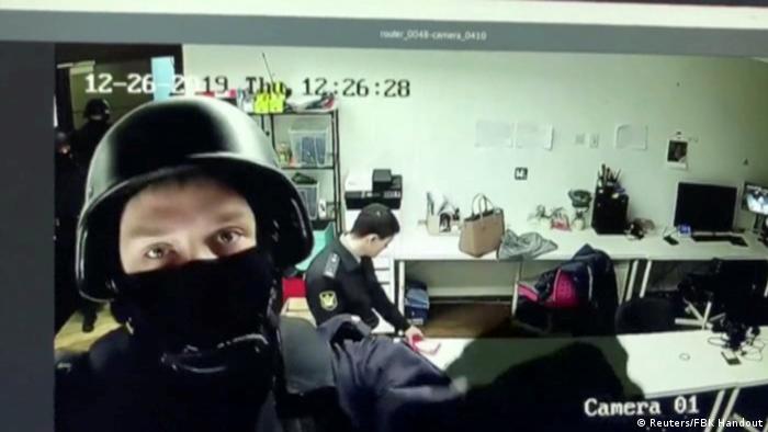 An official looks into a security camera while raiding Alexei Navalny